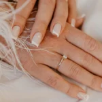 French manucure classique blanche sur des ongles naturels carrés posés sur un tissu blanc