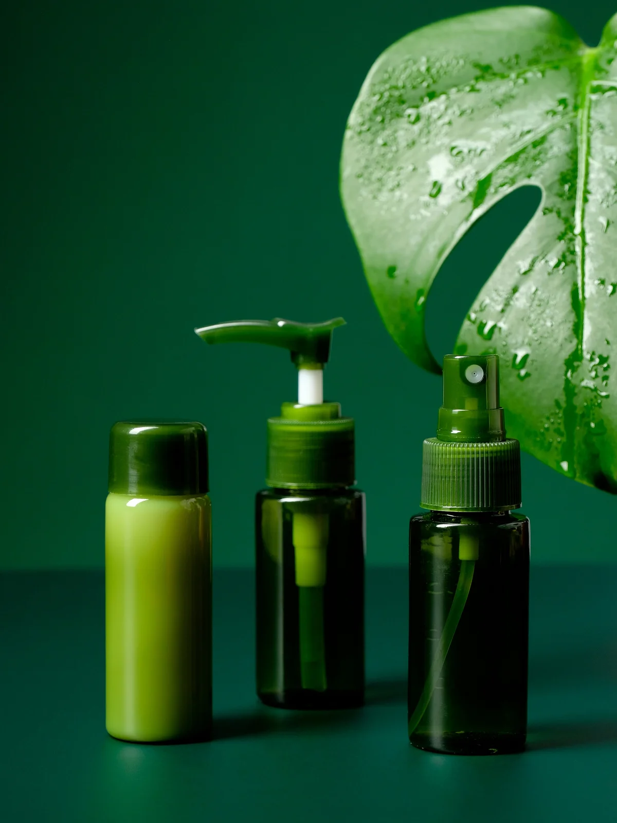 Photo produit de trois gels et crèmes apaisants dans des flacons verts, avec une grande feuille tropicale verte en arrière-plan