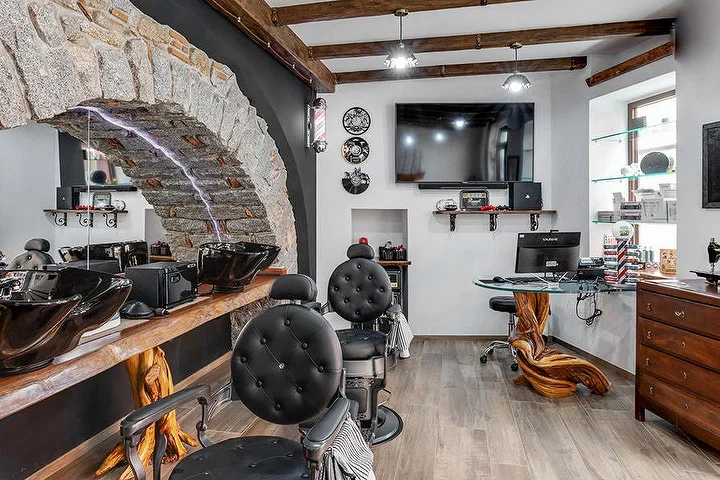 Fauteuil de barbier rustique adossé à une arche de pierre chez La Bottega di Pablo, dans le village de montagne de Lanusei.