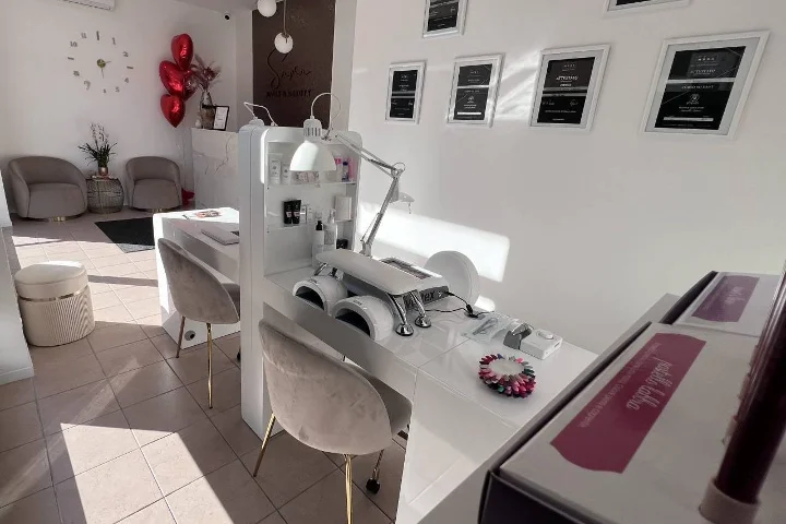 Salon d'ongles blanc chez Sara Nails&Beauty à Tortolì, avec fauteuils en velours gris et certificats encadrés au mur.