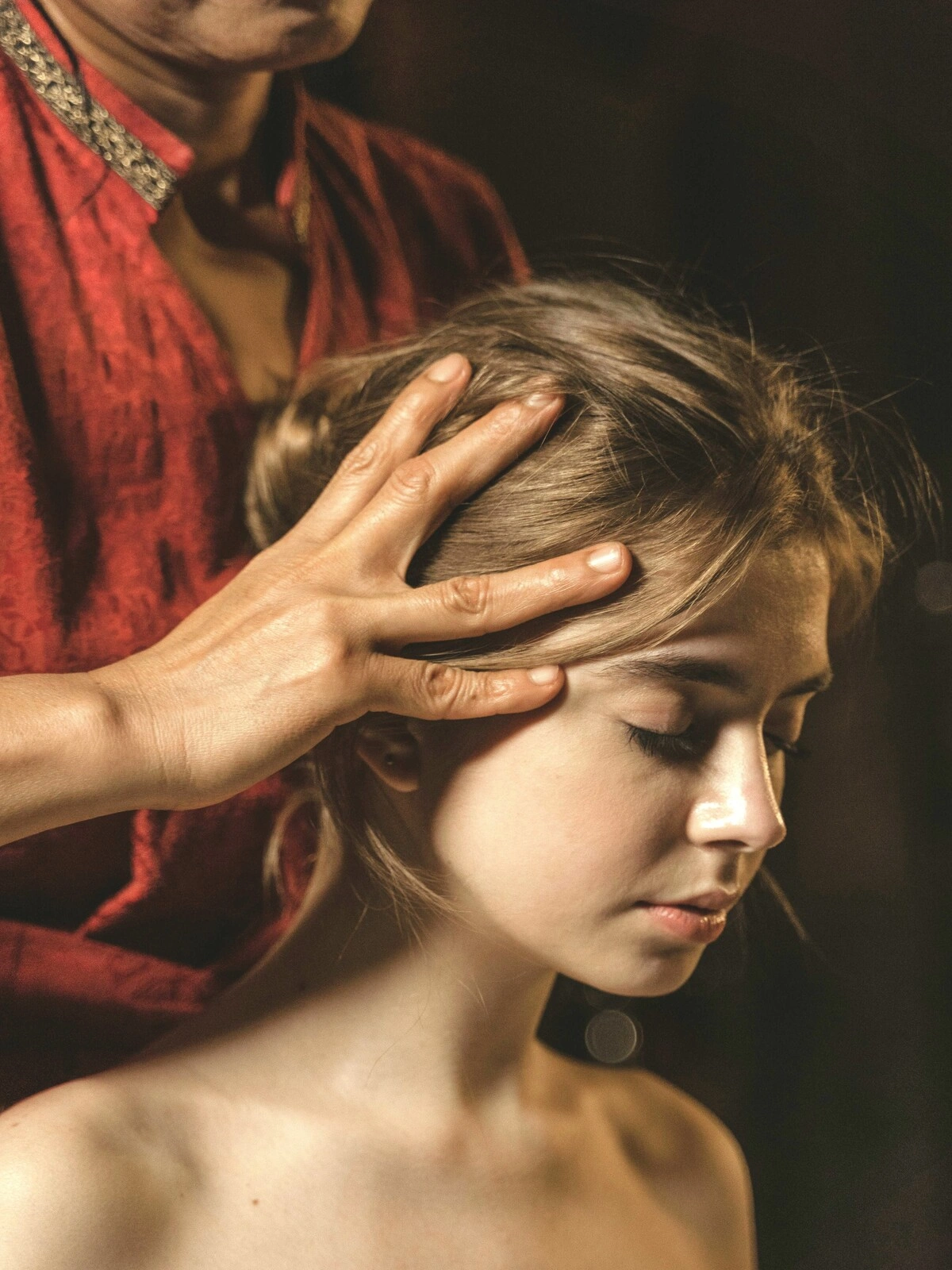 Gros plan sur une femme aux yeux fermés pendant un massage indien de la tête, une praticienne massant son cuir chevelu